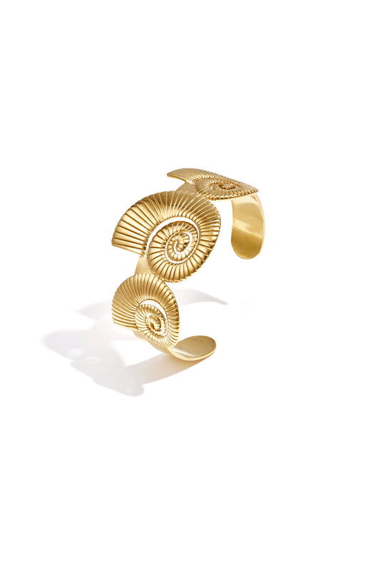 Pulsera tipo brazalete con diseño de conchas en espiral.